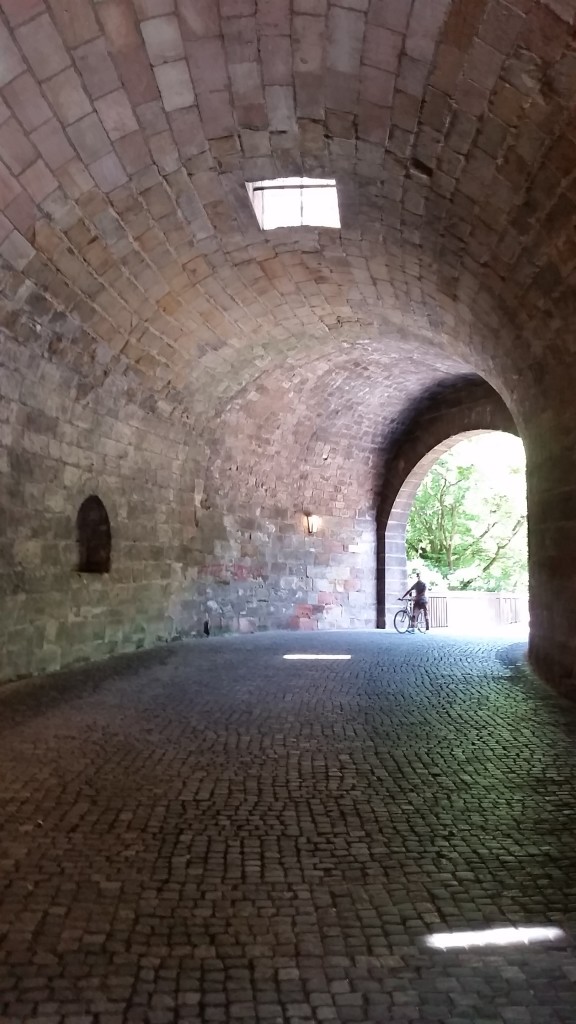Me? Oh, just strolling through this medieval arch like it's no big deal to be swallowed by history. 