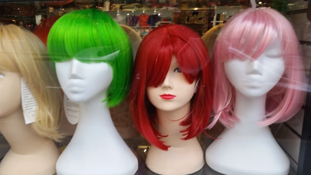 Three wigs on wigstands in a store window
